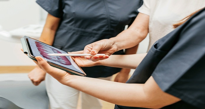 Três pessoas olhando um tablet de perto