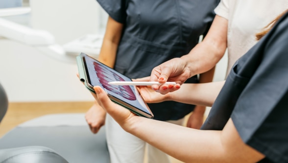 Três pessoas olhando um tablet de perto