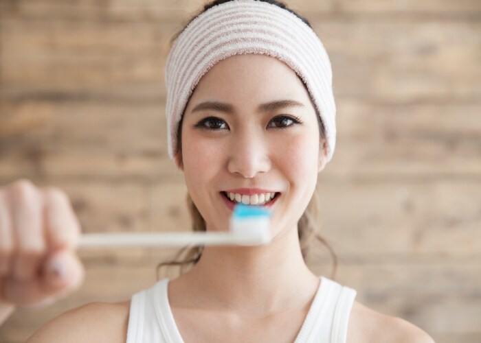 Mulher utilizando creme dental com arginina Mulher utilizando creme dental com arginina