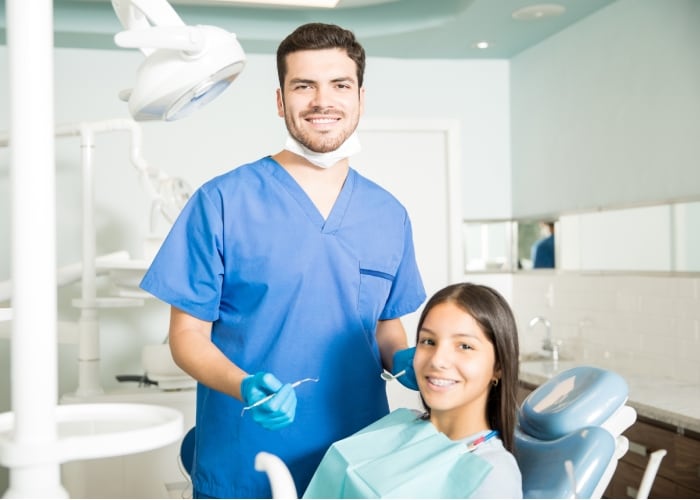 Dentista avaliando o risco de cárie de uma jovem paciente